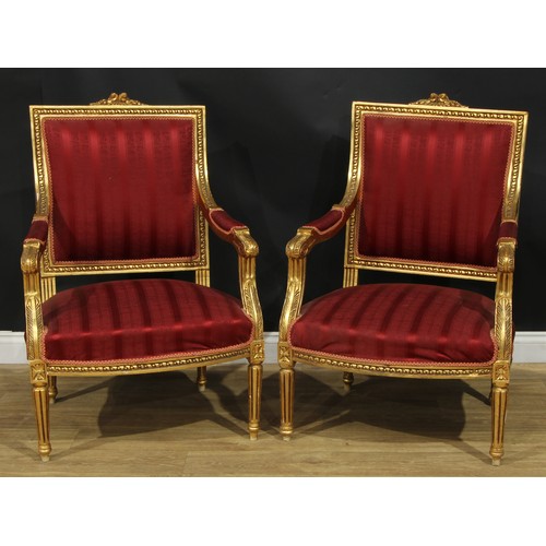 1402 - A pair of Louis XVI Revival giltwood fauteuils, each with stuffed-over upholstery, fluted tapered cy... 