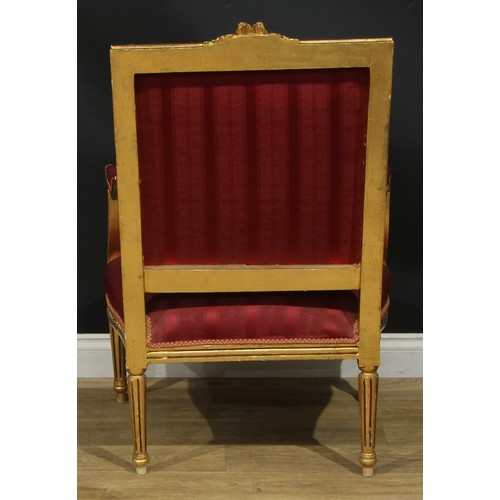 1402 - A pair of Louis XVI Revival giltwood fauteuils, each with stuffed-over upholstery, fluted tapered cy... 