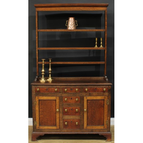 1245 - A George III oak dresser, moulded cornice above three plate racks, the projecting base with a mahoga... 