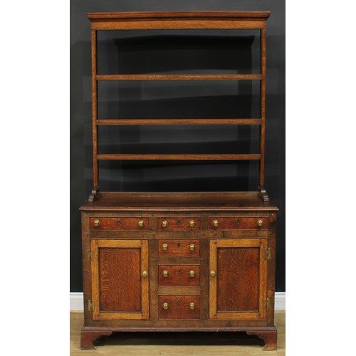 1245 - A George III oak dresser, moulded cornice above three plate racks, the projecting base with a mahoga... 