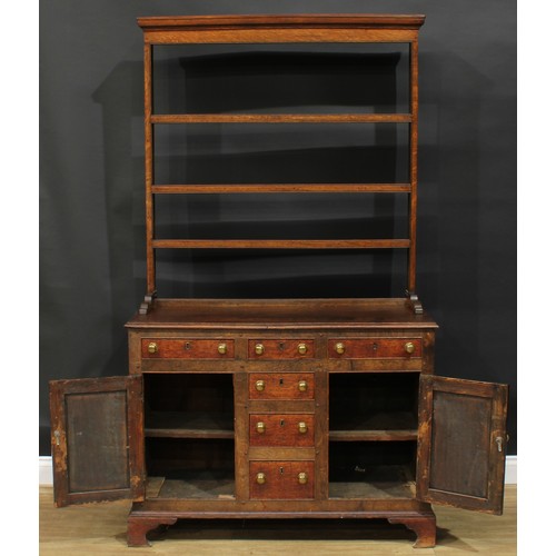 1245 - A George III oak dresser, moulded cornice above three plate racks, the projecting base with a mahoga... 