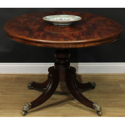 1424 - A Regency mahogany centre table, oval tilting top, turned column, sabre legs, brass capped casters, ... 