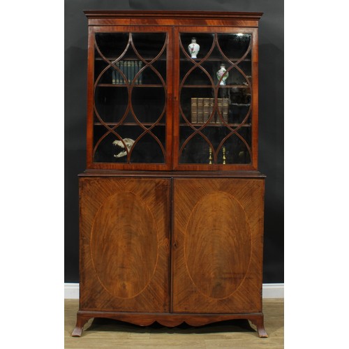 1220 - A George III mahogany library bookcase, outswept cornice above a pair of glazed doors enclosing thre... 