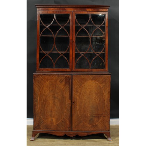 1220 - A George III mahogany library bookcase, outswept cornice above a pair of glazed doors enclosing thre... 