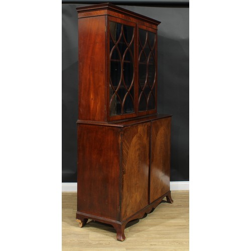 1220 - A George III mahogany library bookcase, outswept cornice above a pair of glazed doors enclosing thre... 