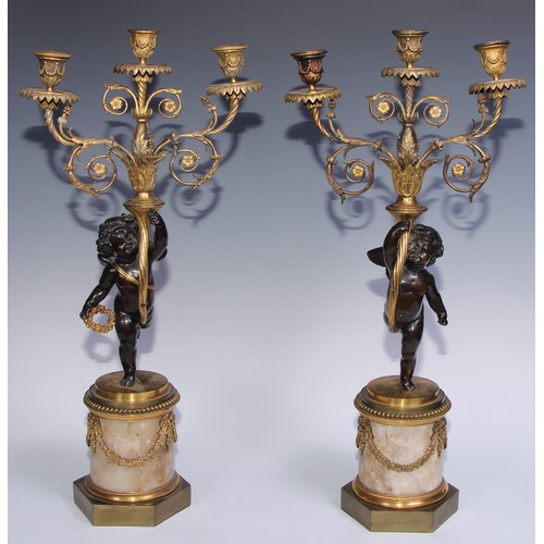 1384 - A pair of 19th century gilt and dark patinated bronze figural three-light candelabra, each cast as a... 