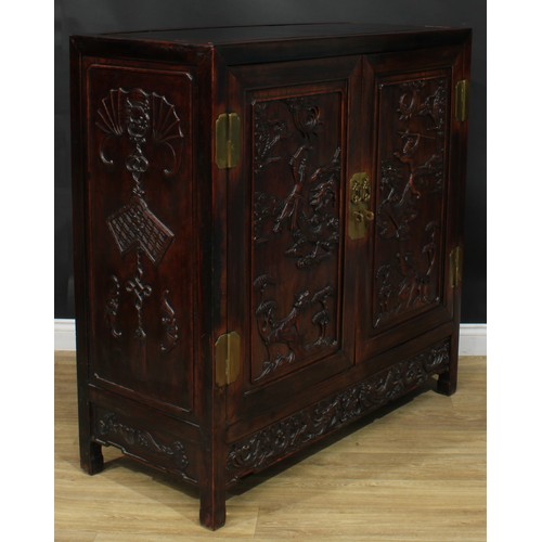 1043 - A Chinese hardwood side cabinet, flush rectangular top above a pair of panel doors carved with duell... 