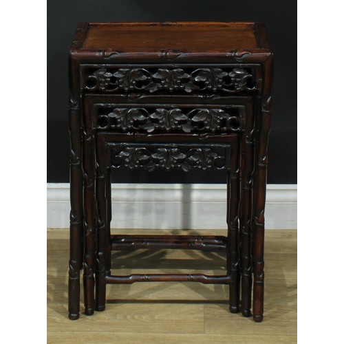 1033 - A Chinese hardwood nest of three occasional tables, each with a rectangular top, the frame carved as... 