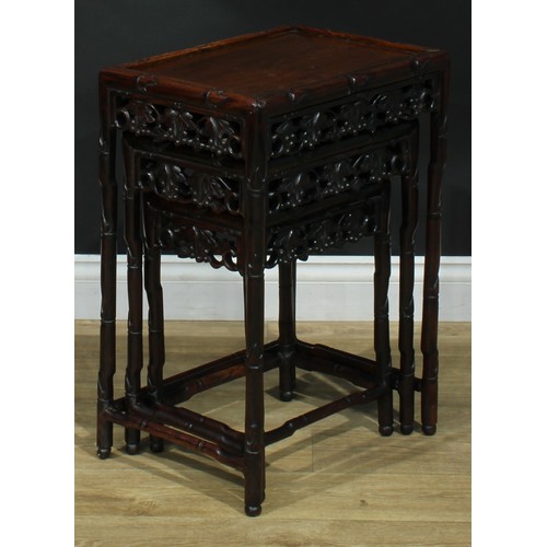 1033 - A Chinese hardwood nest of three occasional tables, each with a rectangular top, the frame carved as... 