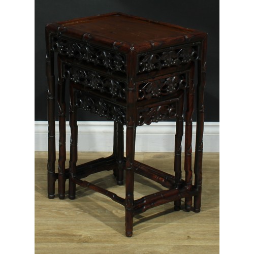 1033 - A Chinese hardwood nest of three occasional tables, each with a rectangular top, the frame carved as... 