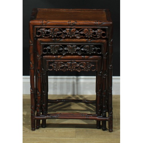 1033 - A Chinese hardwood nest of three occasional tables, each with a rectangular top, the frame carved as... 