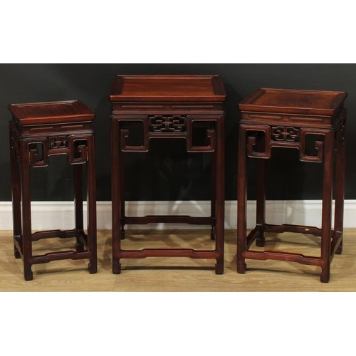 1034 - A Chinese hardwood nest of three waisted occasional tables, each with a square top above a shaped fr... 