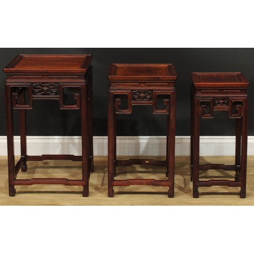 1034 - A Chinese hardwood nest of three waisted occasional tables, each with a square top above a shaped fr... 