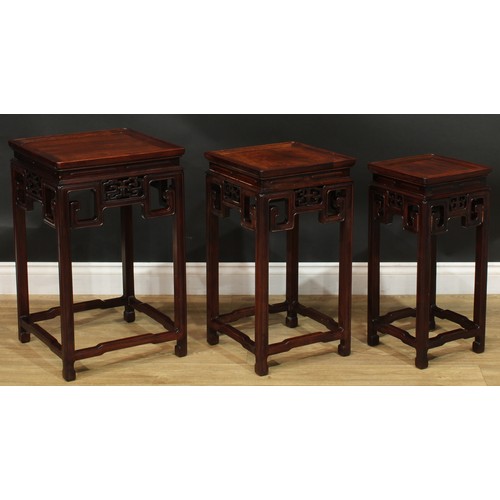 1034 - A Chinese hardwood nest of three waisted occasional tables, each with a square top above a shaped fr... 