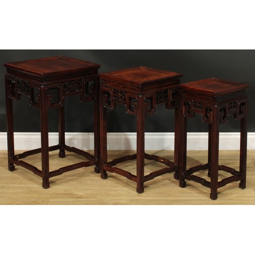 1034 - A Chinese hardwood nest of three waisted occasional tables, each with a square top above a shaped fr... 