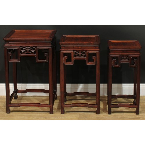 1034 - A Chinese hardwood nest of three waisted occasional tables, each with a square top above a shaped fr... 