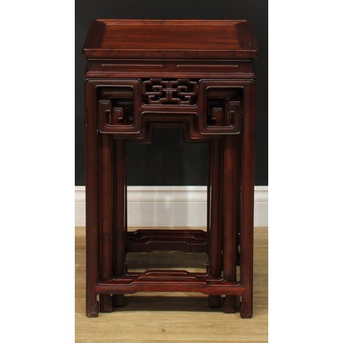 1034 - A Chinese hardwood nest of three waisted occasional tables, each with a square top above a shaped fr... 