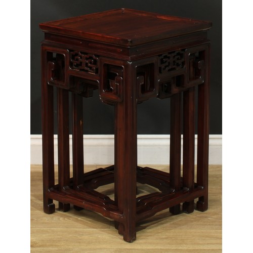 1034 - A Chinese hardwood nest of three waisted occasional tables, each with a square top above a shaped fr... 