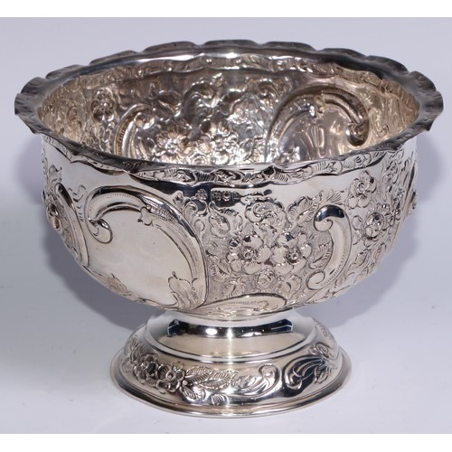 279 - An Edwardian silver pedestal bowl, chased with flowers, foliage and C-scrolls, wavy rim, domed base,... 