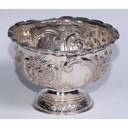 279 - An Edwardian silver pedestal bowl, chased with flowers, foliage and C-scrolls, wavy rim, domed base,... 