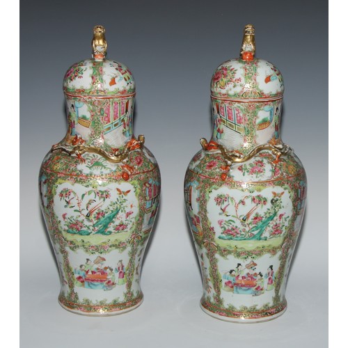 777 - A pair of Cantonese baluster vases and covers, painted in the famille rose palette with figures, bir... 