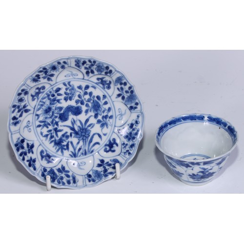 784 - A pair of Chinese wine cups or tea bowls and saucers, painted in tones of underglaze blue with flowe... 