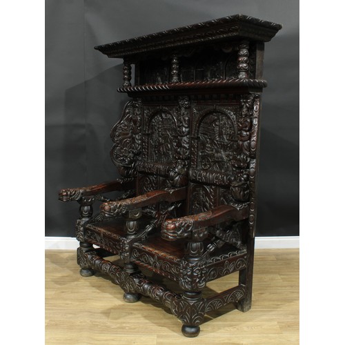 1280 - A large 17th century style oak settle, carved throughout with native folk scenes, grotesque masks an... 