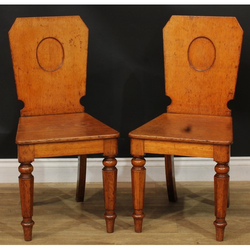 1409 - A pair of Victorian oak hall chairs, each with a shaped rectangular back with vacant oval crest rese... 