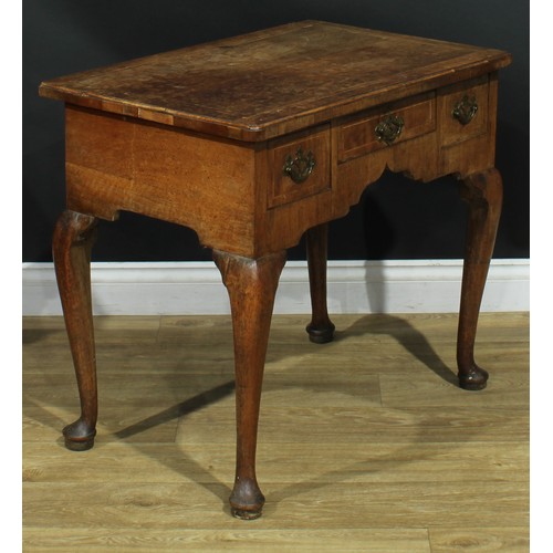 1100 - A George II walnut lowboy, crossbanded quarter-veneered top above three frieze drawers, shaped apron... 