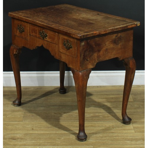 1100 - A George II walnut lowboy, crossbanded quarter-veneered top above three frieze drawers, shaped apron... 