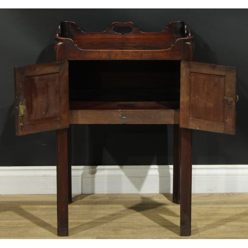 1233 - A George III mahogany tray top bedroom night cupboard, shaped and pierced gallery above a pair of ra... 