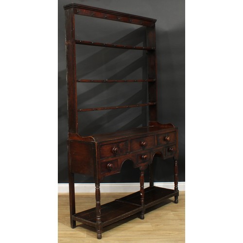 1167 - A George III oak potboard dresser, moulded cornice above three plate racks, the projecting base with... 