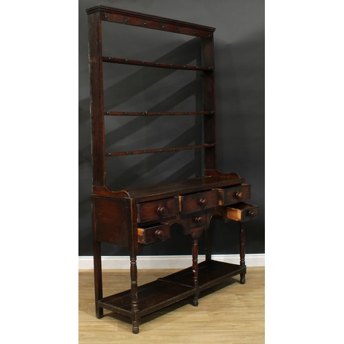 1167 - A George III oak potboard dresser, moulded cornice above three plate racks, the projecting base with... 