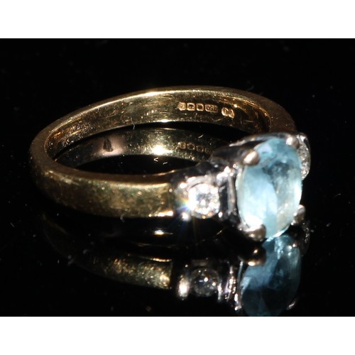 367 - An 18ct gold ring, the central oval cut aquamarine flanked by a pair of brilliant cut diamonds, ring... 