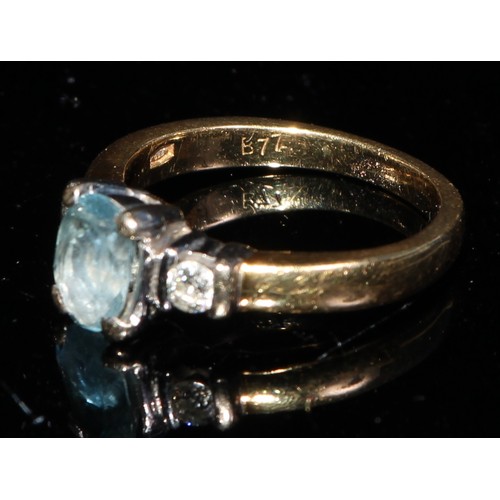 367 - An 18ct gold ring, the central oval cut aquamarine flanked by a pair of brilliant cut diamonds, ring... 