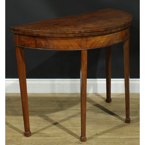 1115 - A George III mahogany demilune tea table, hinged top, tapered square legs, one rear concealing a sec... 