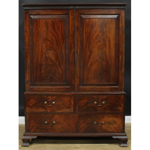 1222 - A George III mahogany linen press, nulled cornice above a pair of flame veneered panel doors enclosi... 