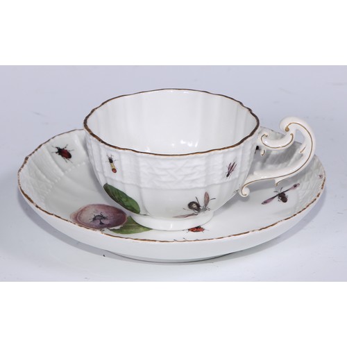 524 - A Meissen cup and saucer, painted in polychrome with insects, fruit and pea pods, on a moulded groun... 