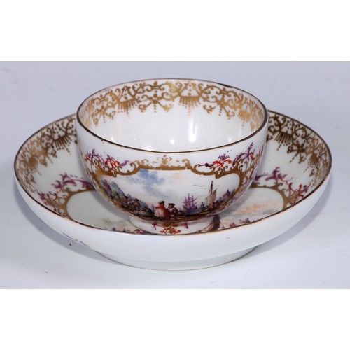 525 - A Meissen tea bowl and saucer, painted in polychrome with harbour views, gilt borders, the saucer 12... 