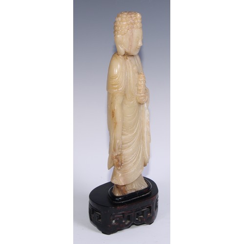 799 - A Chinese soapstone figure, carved as Buddha holding a pagoda, carved hardwood stand, 41cm high, ear... 