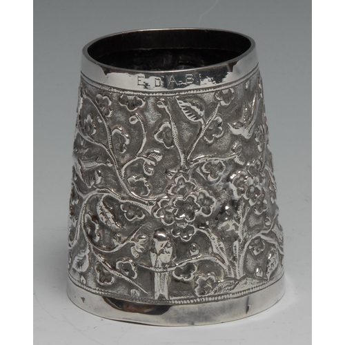 287 - An Indian silver spreading cylindrical mug, chased with birds and flowering branches, 8.5cm high, c.... 