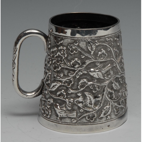 287 - An Indian silver spreading cylindrical mug, chased with birds and flowering branches, 8.5cm high, c.... 