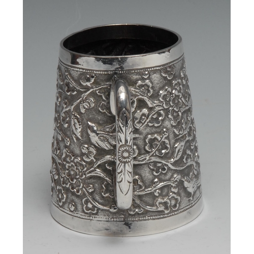 287 - An Indian silver spreading cylindrical mug, chased with birds and flowering branches, 8.5cm high, c.... 