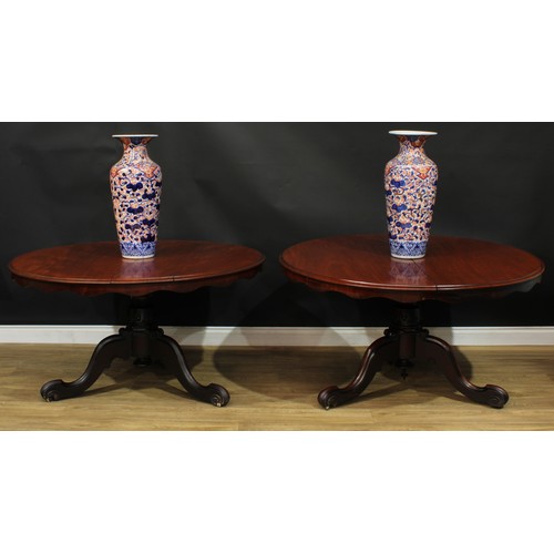 1408 - A pair of Victorian mahogany centre tables, each with a circular tilting top with moulded edge and w... 