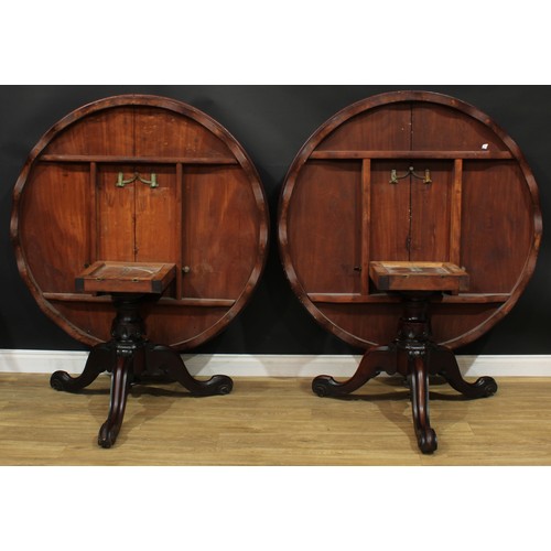 1408 - A pair of Victorian mahogany centre tables, each with a circular tilting top with moulded edge and w... 