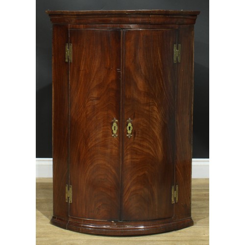 1237 - A George III mahogany wall hanging bowfront corner cupboard, moulded cornice above a pair of doors e... 