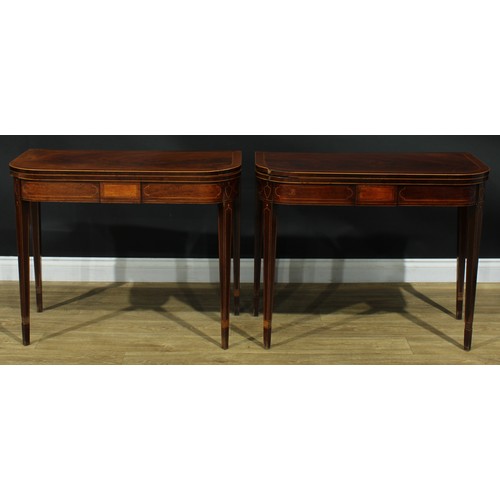 1394 - A pair of George III mahogany D-shaped card tables, each with a hinged crossbanded top enclosing a b... 