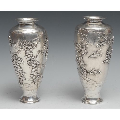 195 - A pair of Japanese silver ovoid vases, chased with birds and blossoming prunus, on a textured ground... 