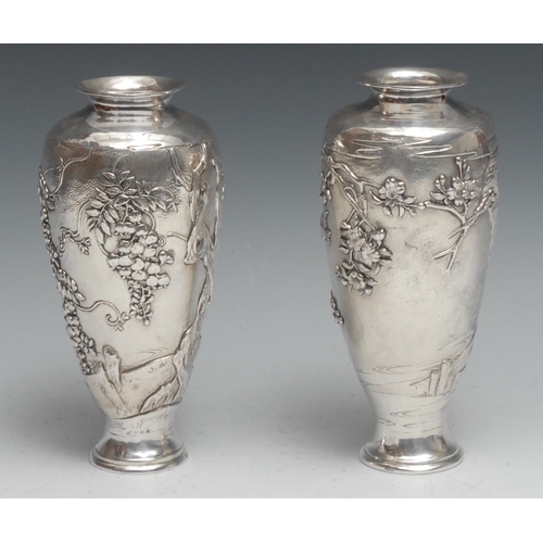 195 - A pair of Japanese silver ovoid vases, chased with birds and blossoming prunus, on a textured ground... 