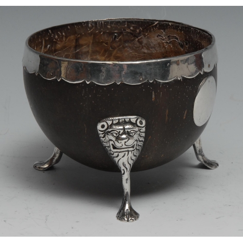 253 - An 18th century silver mounted coconut cup, probably Irish, shaped pendant rim, three lion monopodia... 